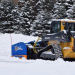 Compact track loader plowing snow