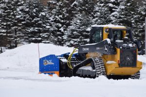 Compact track loader plowing snow